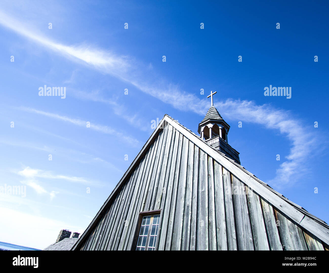 Kirchturm mit Platz kopieren. Land hölzerne Kirchturm gegen einen sonnigen blauen Himmel mit einem hölzernen Kreuz auf der Spitze. Stockfoto