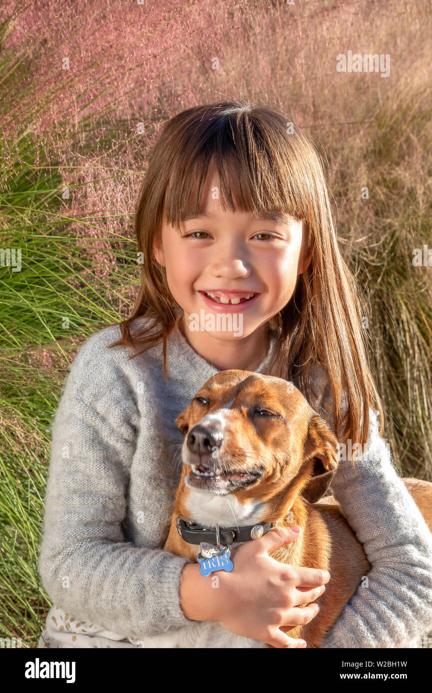 Sieben Jahre alten Mädchen lachend mit ihrem Hund im Park Stockfoto