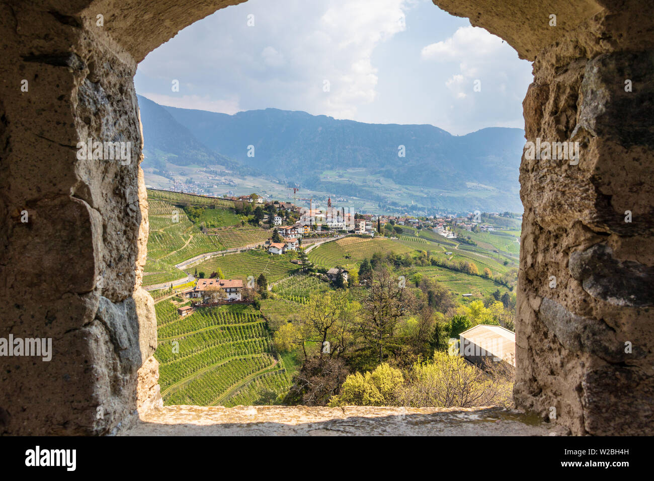 Dorf Tirol, Dorf Tirol bei Meran im Meraner Land, mit Wein Plantagen und die Alpen im Hintergrund. Durch die Fenster von Schloss Tirol eingerahmt. Südtirol, Italien Stockfoto