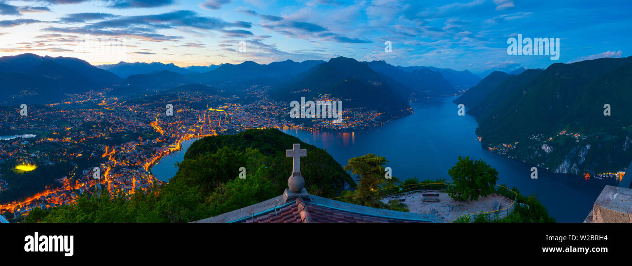 Erhöhte Sicht über Lugano, vom Monte San Salvatore leuchtet in der Dämmerung, Lago di Lugano, Tessin, Schweiz Stockfoto