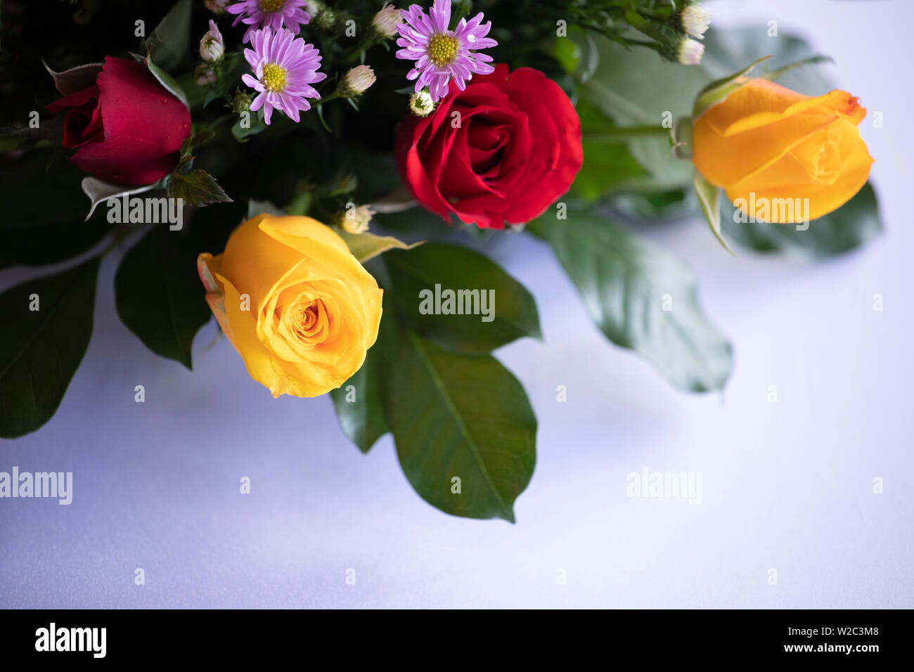 Gelbe und rote Rosen gegen eine weiße Tischdecke, Tabelle Einstellung für Feier Stockfoto