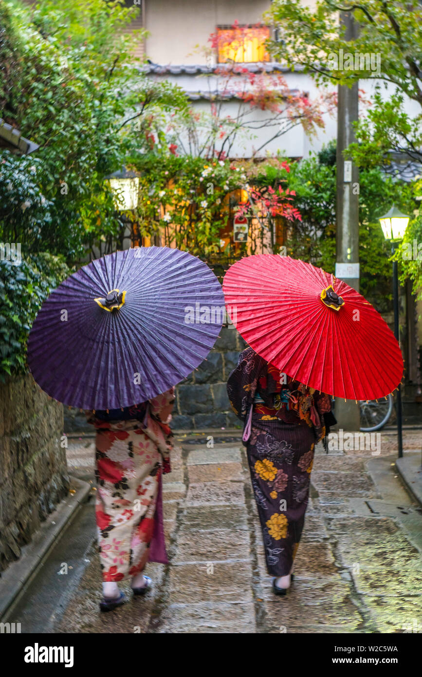 Frauen in traditioneller Kleidung mit Sonnenschirmen zu Fuß durch Kyoto, Japan Stockfoto