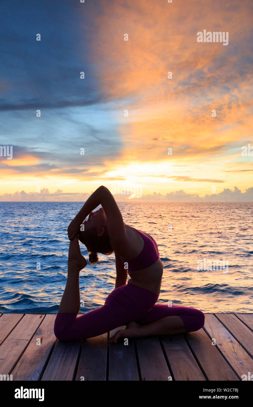 Malediven, Süd Ari Atoll, Thudufushi Island, Diamanten Thudufushi Resort, Frau Yoga bei Sonnenuntergang (MR) Stockfoto