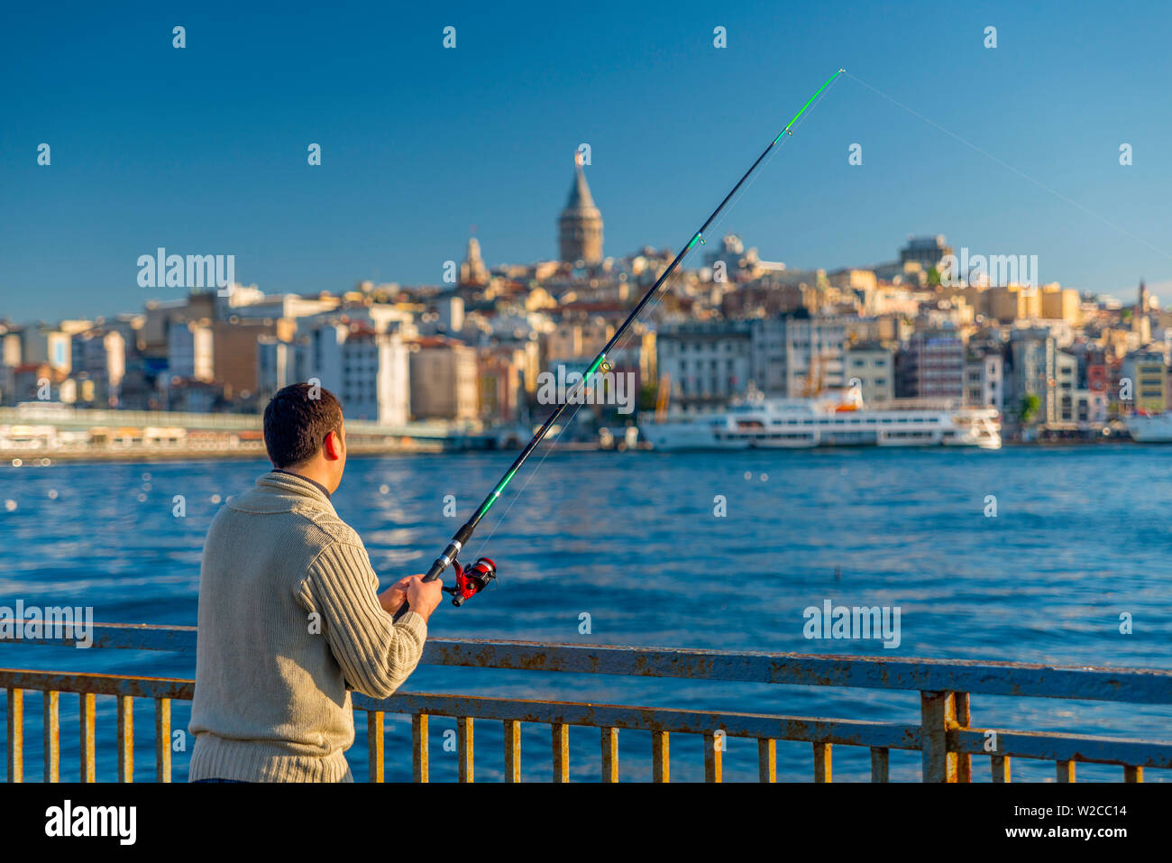 Türkei, Istanbul, Canakkale, das Goldene Horn, Galata Turm im Hintergrund, Mann angeln Stockfoto