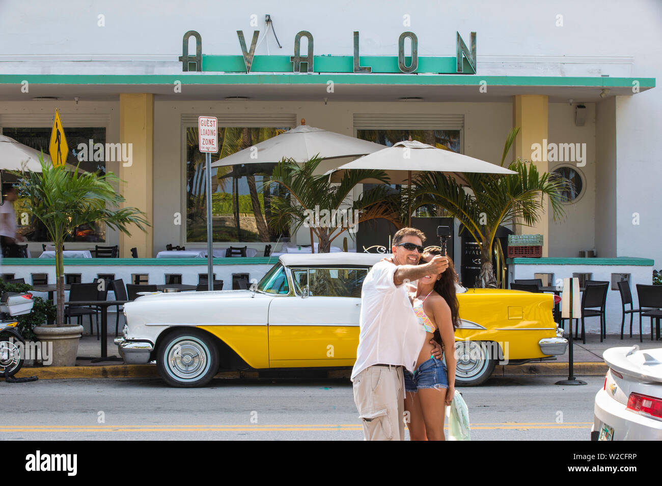 Usa, Miami, Miami Beach, South Beach, Ocean Drive, Paar ein selfie infront von gelben und weißen Oldtimer außerhalb Avalon Hotel geparkt Stockfoto