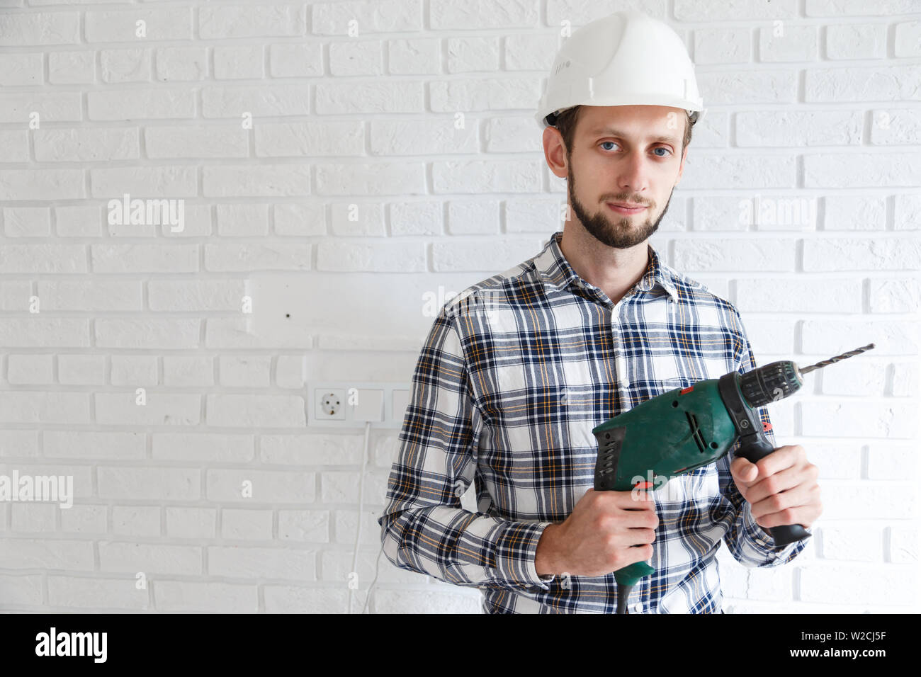 Man-Werkstatt in Schutzkleidung Schutzhelm mit hsmmer Bohren Stockfoto