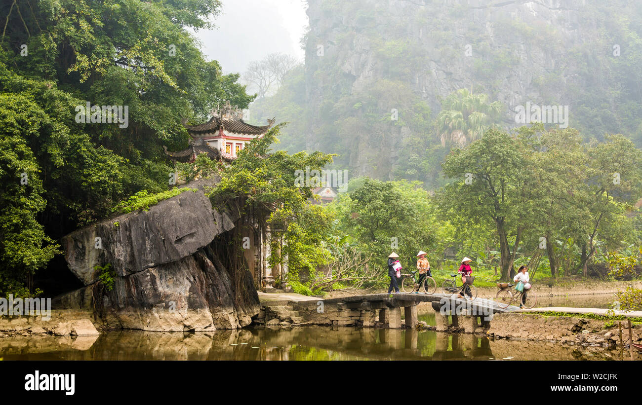 Frau Kreuzung Brücke mit Fahrrad zu Tempel, Tam Coc nr Ninh Binh, nr in Hanoi, Vietnam Stockfoto