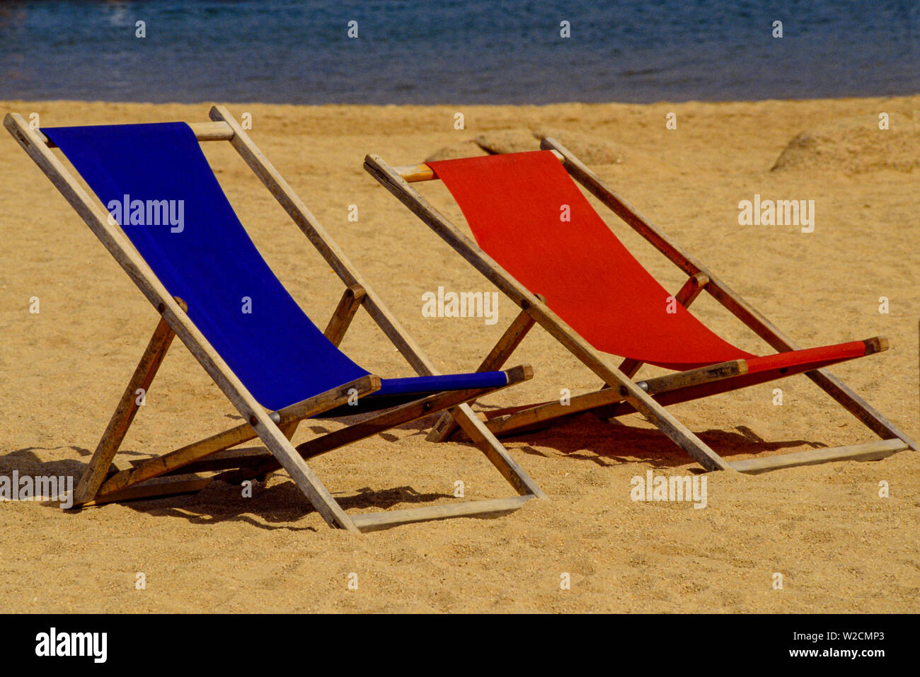 Sardinien, 1990. Rot und Blau waren Liegestühle auf dem Sandstrand. Foto: © Simon Grosset. Archiv: Bild von einem ursprünglichen Transparenz digitalisiert. Stockfoto