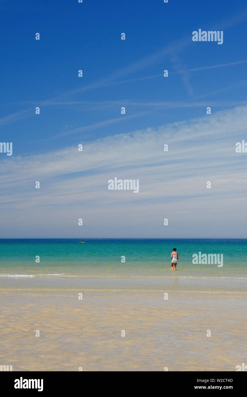 Eine Frau, die zu Fuß ins Meer auf godrevy Beach, Cornwall Stockfoto