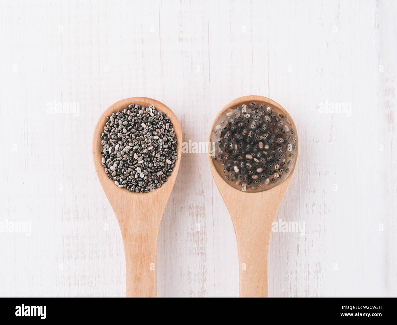 Trocken und Nass Chia Chia Samen Samen oder Chia-Ei in Holzlöffel auf weißem Holz- Hintergrund. Eiersatzprodukte, Eiern, veganer Eier Konzept ersetzen Stockfoto