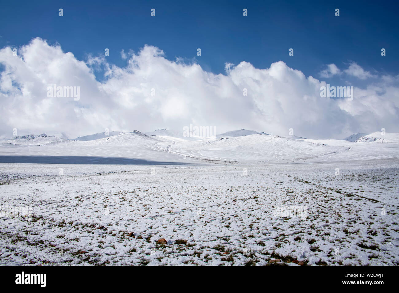 Blick auf den verschneiten Wiesen und Hügel gegen den Himmel mit Wolken. Das Reisen in Kirgistan. Stockfoto