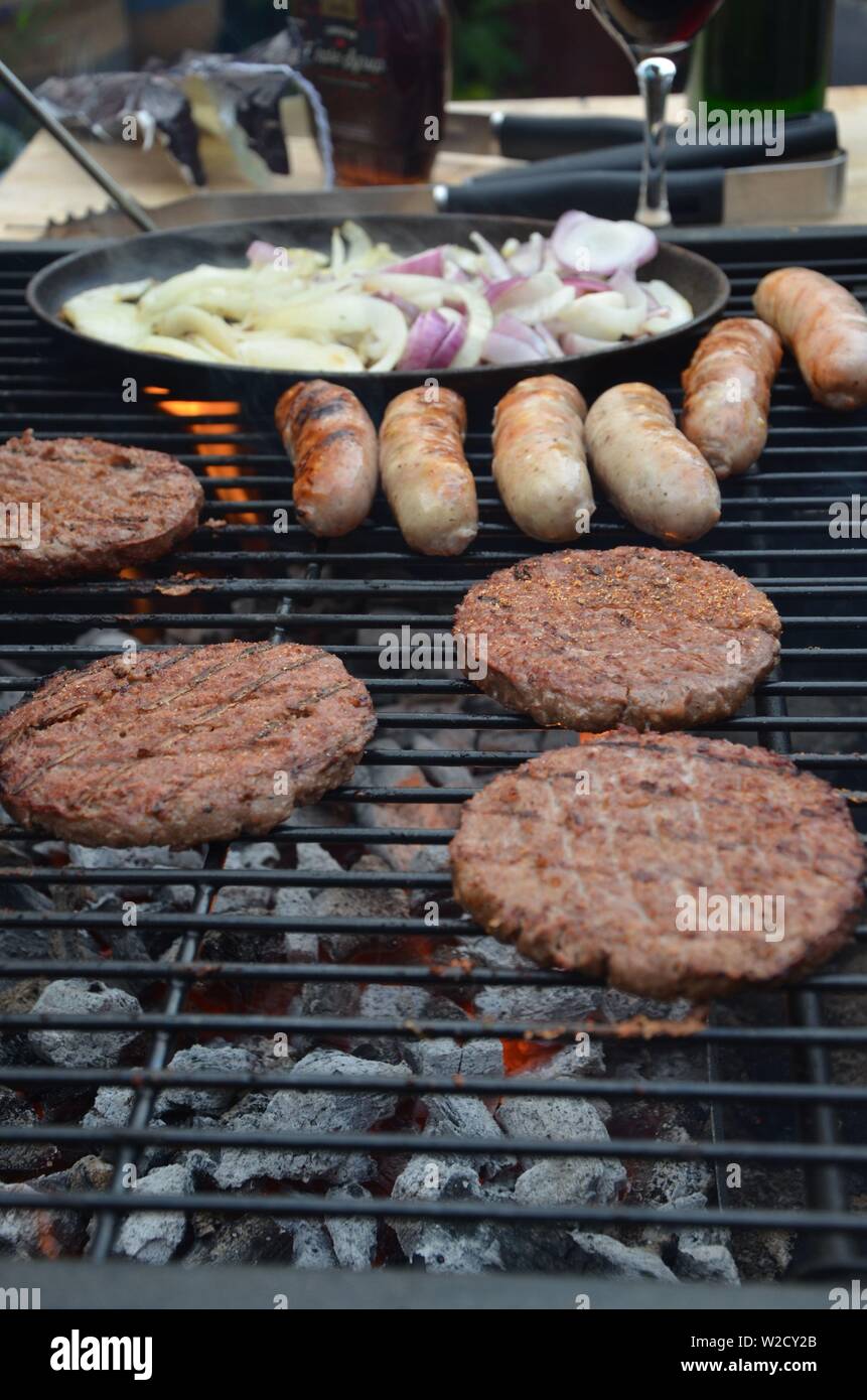 Würstchen und Rindfleisch Burger Kochen auf dem Grill Stockfoto