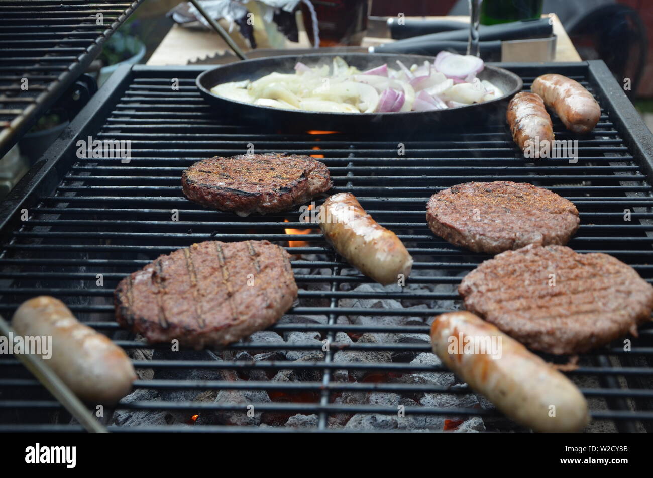Würstchen und Rindfleisch Burger Kochen auf dem Grill Stockfoto