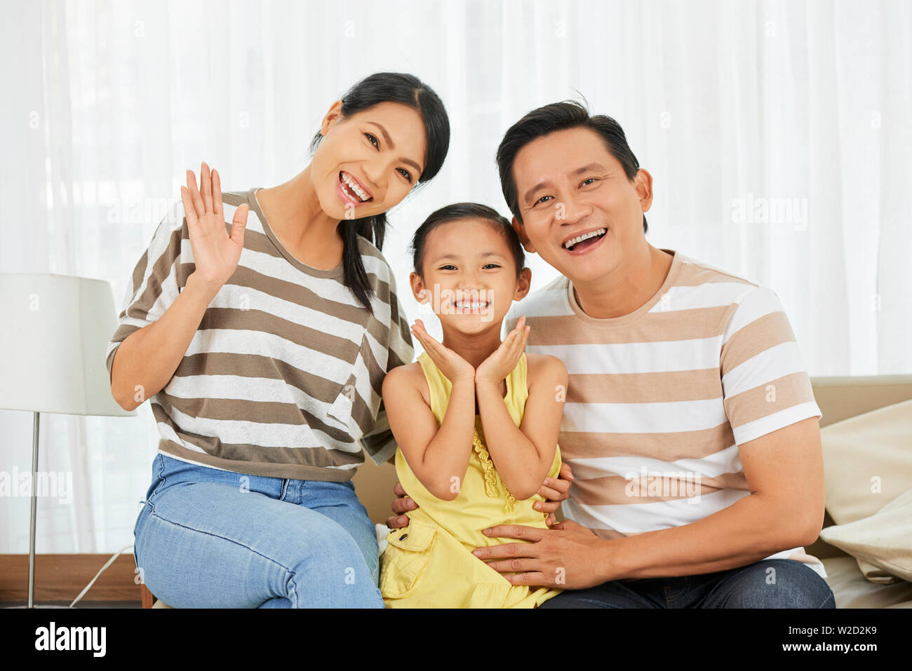Portrait von glücklichen asiatischen Familie von drei Sitzen auf einem Sofa zusammen Posieren und lächelnd an der Kamera zu Hause. Stockfoto