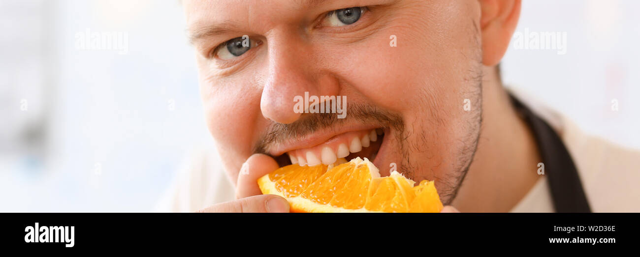 Professioneller Koch Bite Orange Slice Portrait Stockfoto