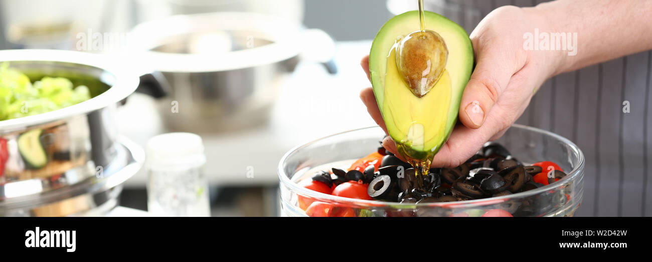 Männliche Hände goß Öl halbiert Tropischen Avocado Stockfoto