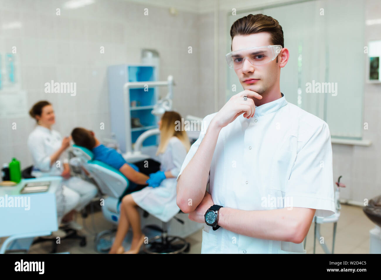 Zahnmedizinische Klinik. Porträt eines professionellen Zahnarzt auf dem Hintergrund einer Arbeitsgruppe der Ärzte. Konzept der medizinischen Ausbildung und der Krankenversicherung. Stockfoto