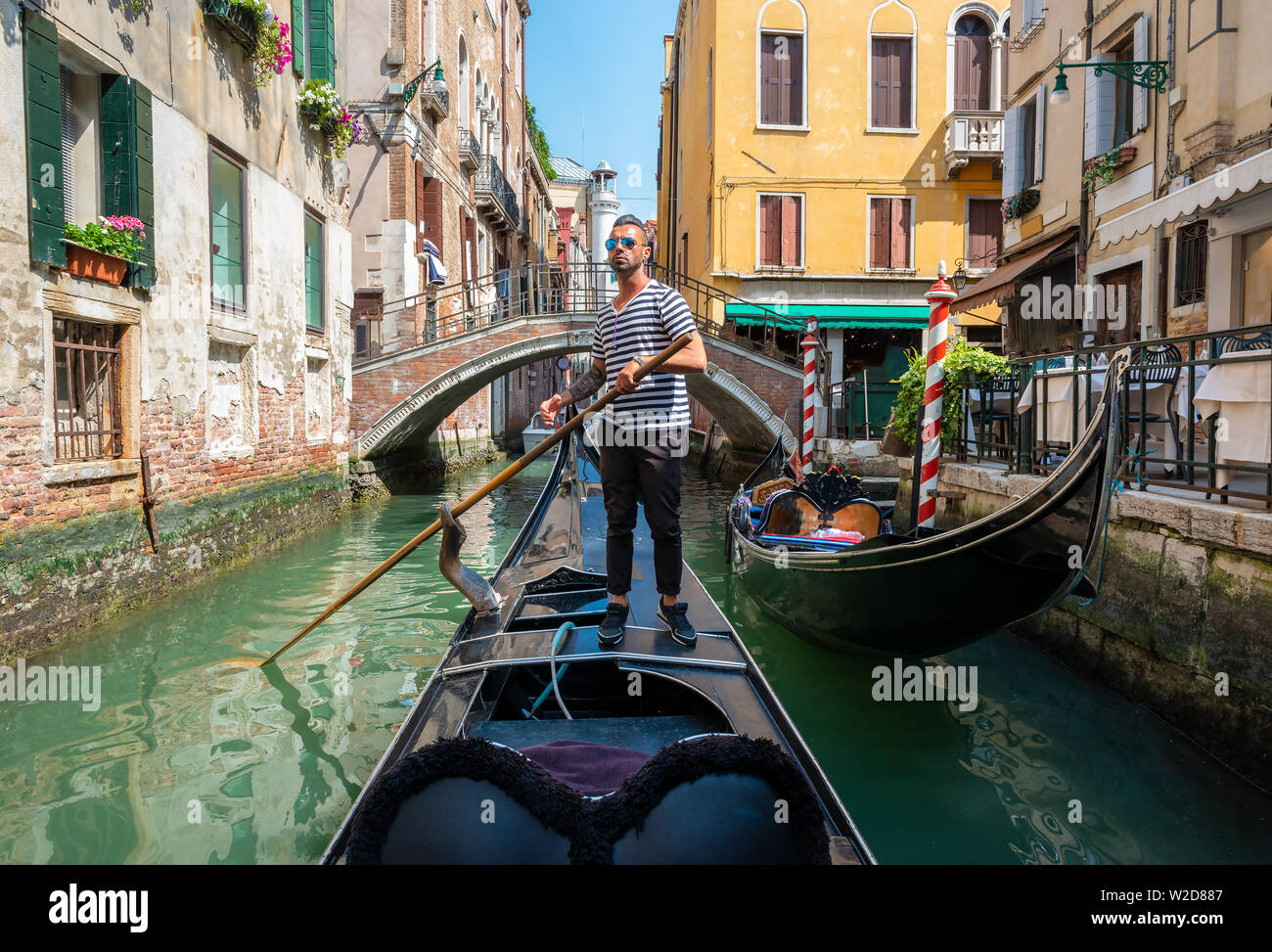 Gut aussehend Gondoliere während der Gondelfahrt auf der Straße von Venedig, Italien Stockfoto