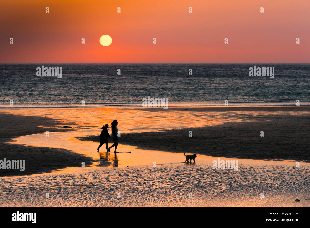 Menschen in Silhouette als einen wunderschönen Sonnenuntergang setzt auf den Fistral Beach in Newquay in Cornwall gesehen. Stockfoto