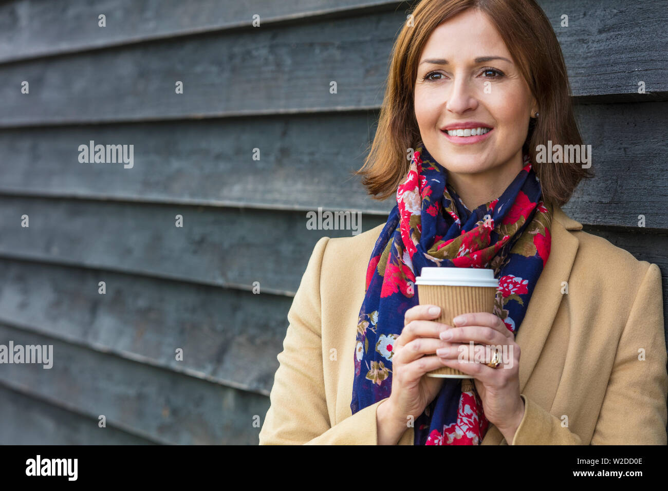 Portraitfotos eines attraktiven, erfolgreiche und glückliche Frau mittleren Alters weiblichen außerhalb trinken Kaffee in eine Tasse zum Mitnehmen. Stockfoto