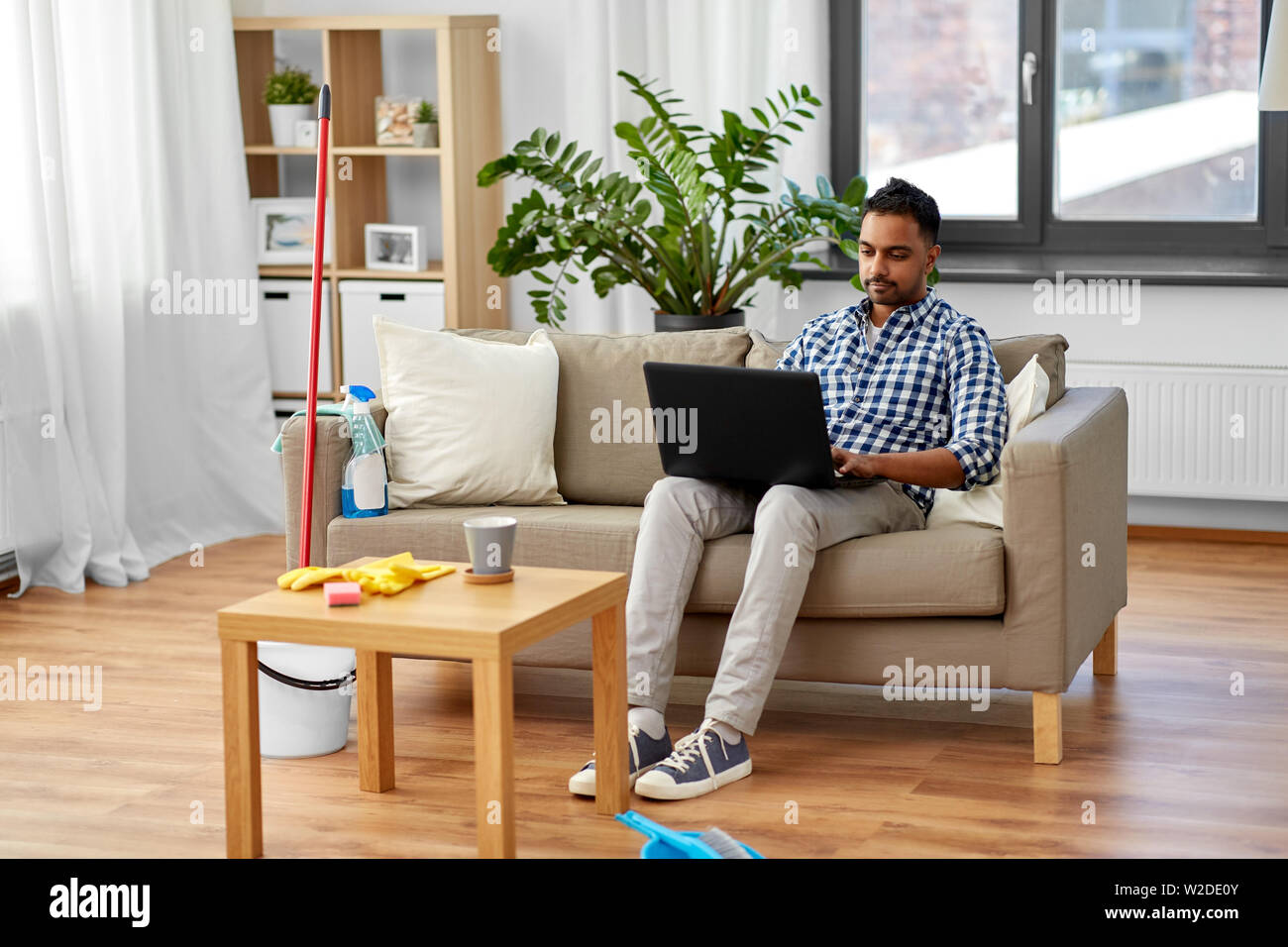 Mann mit Laptop nach Hause Reinigung Stockfoto