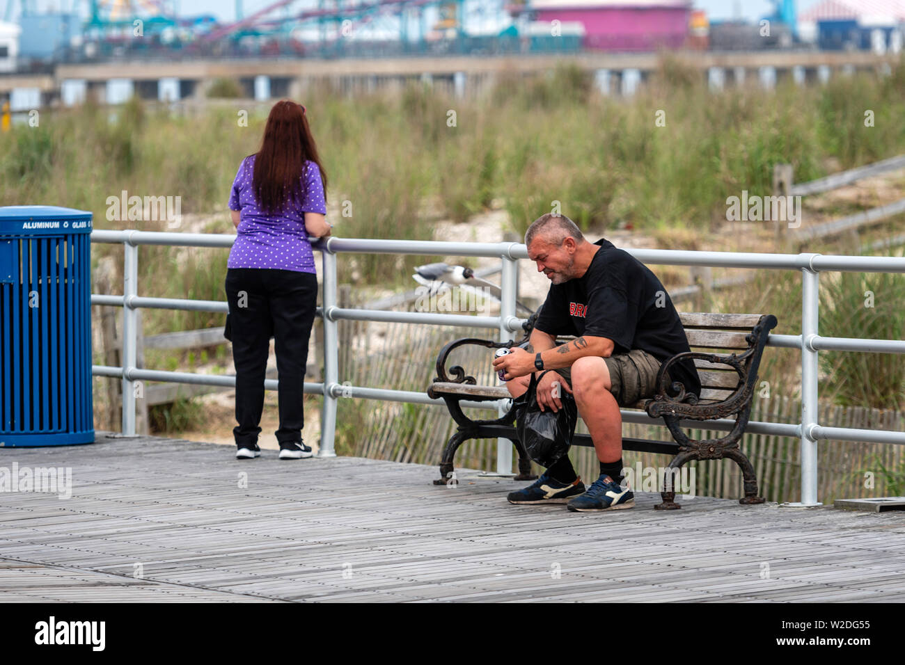 ATLANTIC CITY, NEW JERSEY - Juni 18, 2019: Ein Mann auf einer Bank am Rand von einem Holzsteg ruht. Stockfoto