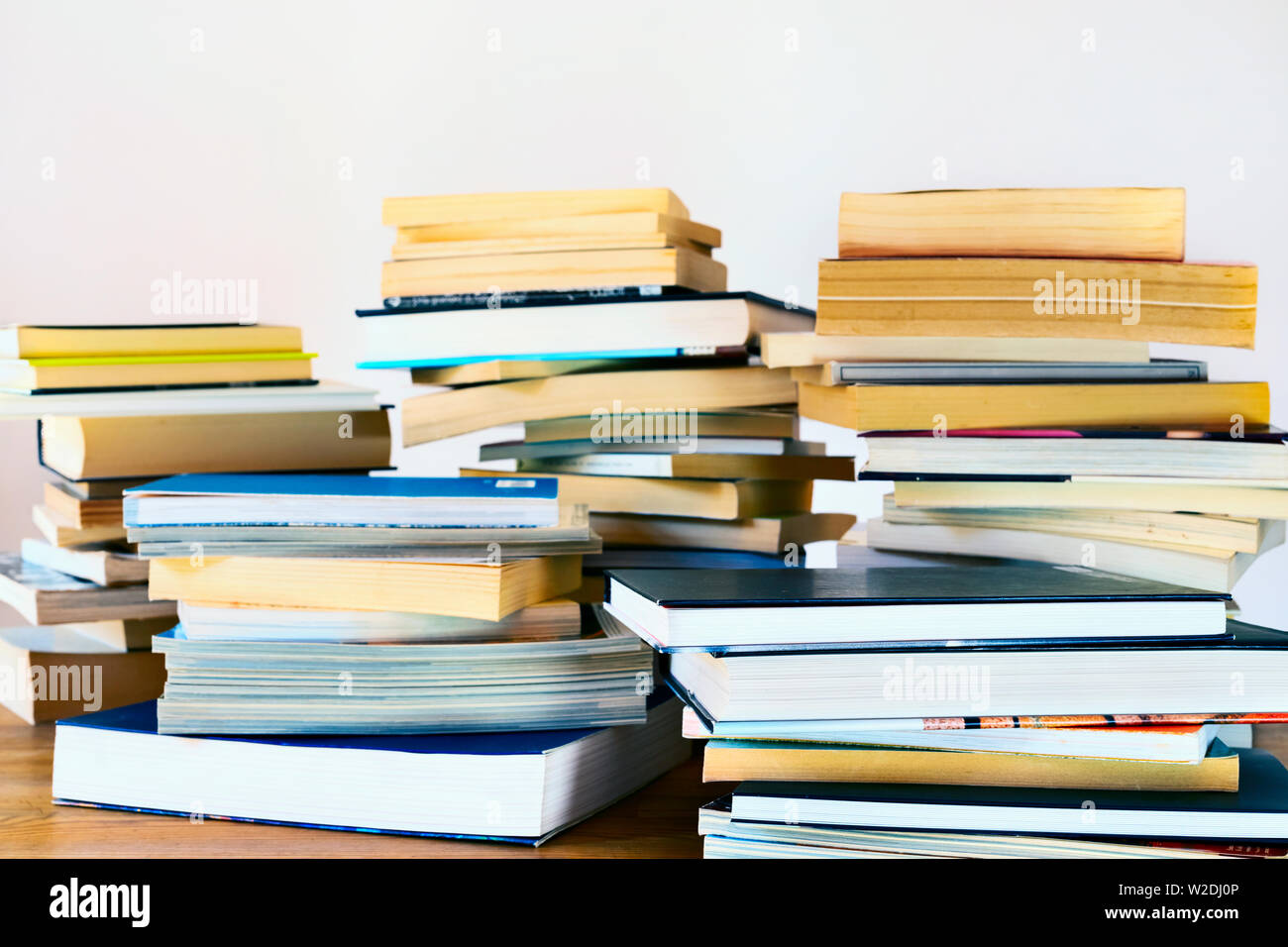 Mehrere Stapel verschiedener Bücher auf einem Holztisch, Bücher gebrauchte und neue, Stockfoto