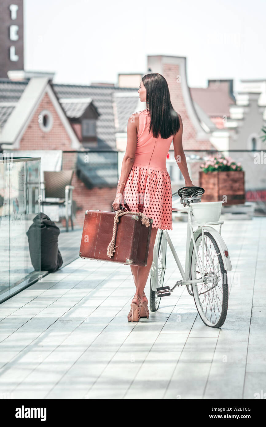 Schöne brünette Frau mit Fahrrad und Koffer Stockfoto