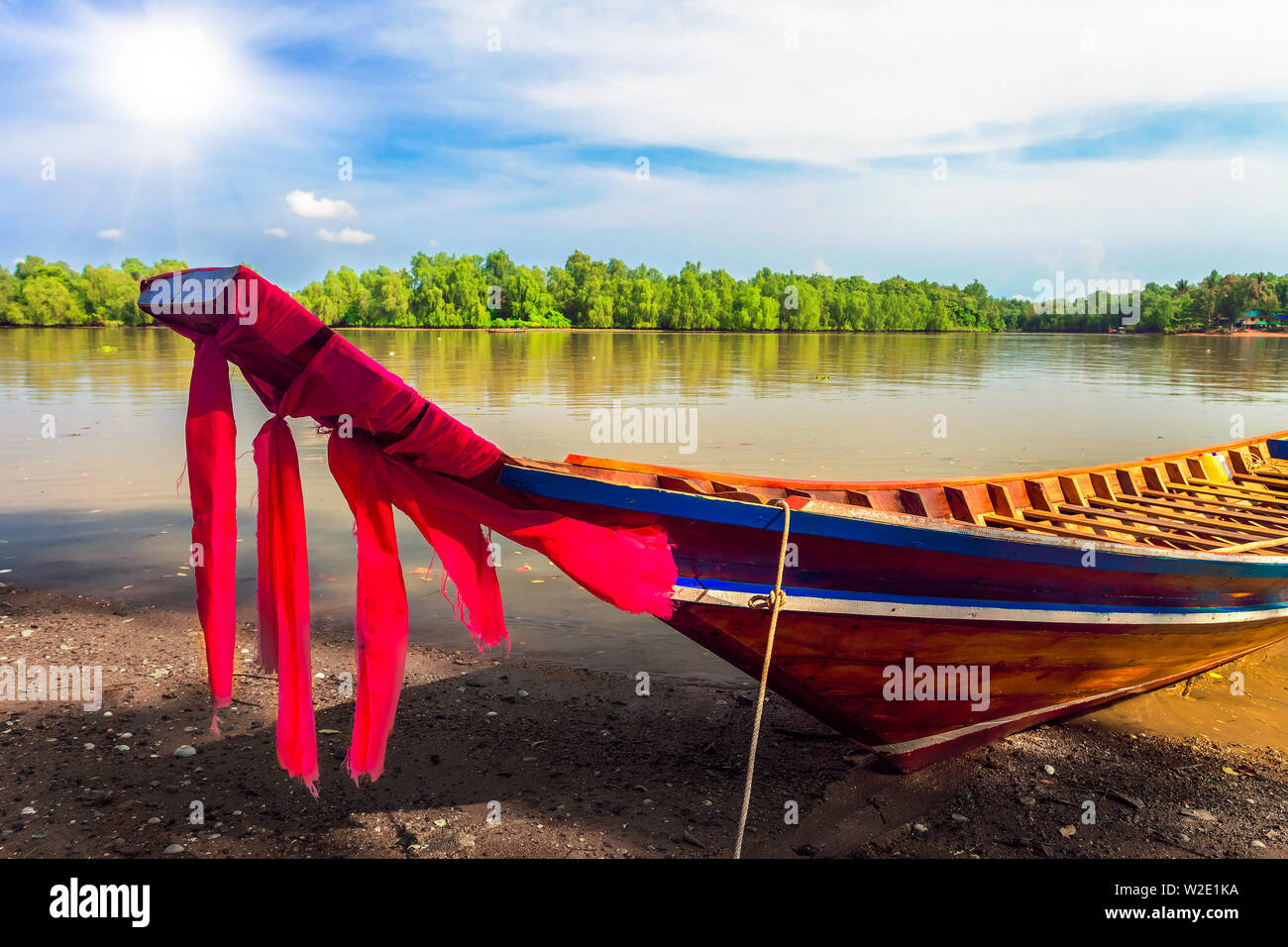 Dekorative Holz- Boot auf dem Wasser und grüne Bäume auf Bank Stockfoto