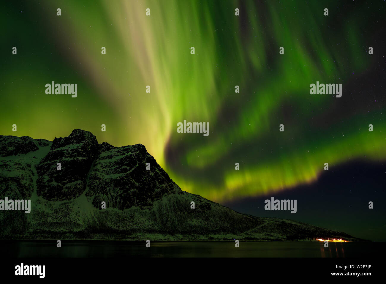 Schweres grünes Nordlicht über den verschneiten Berg Ramnafjellet im Winter, Troms, Norwegen Stockfoto