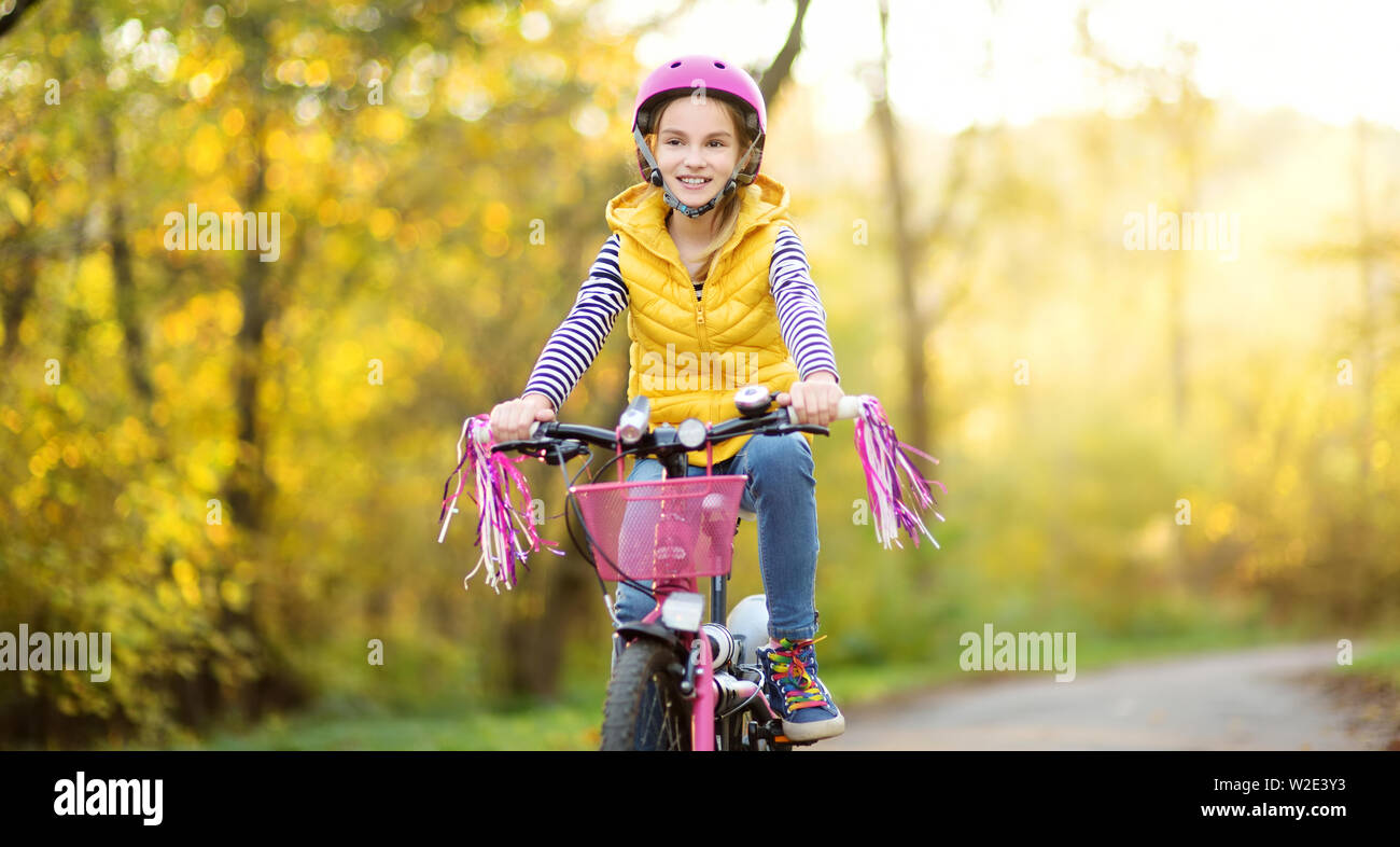Adorable junge Mädchen mit dem Fahrrad in einem Stadtpark an sonnigen Herbsttag. Aktive Familie Freizeit mit Kindern. Kind tragen Helm beim Reiten eines bicy Stockfoto
