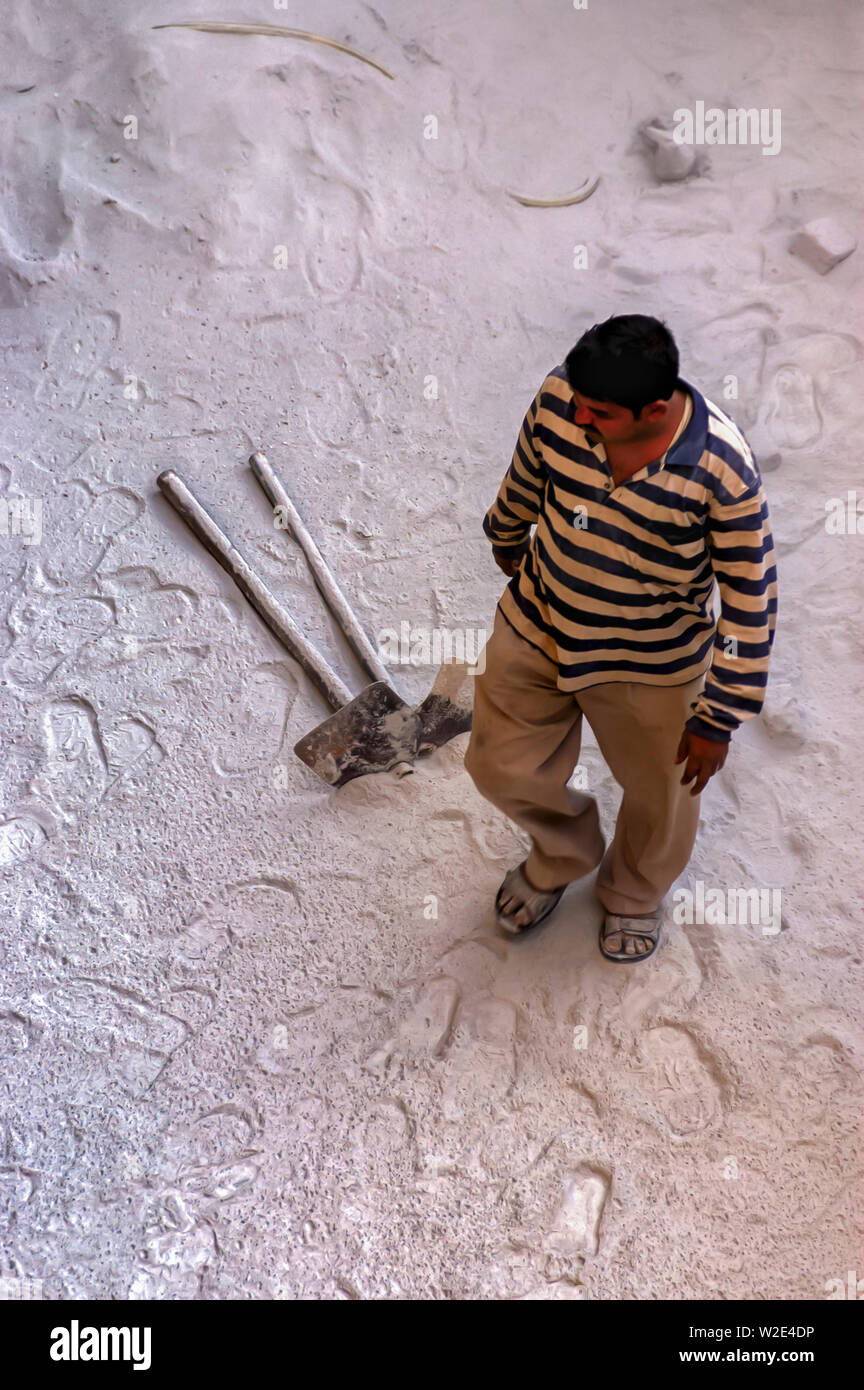 Einen Brunnen bohren Arbeitnehmer Spaziergänge auf einer Schicht von feinem Staub mit zahlreichen Spuren markiert. Zwei Garten hacken gesehen liegen auf dem Staub. Stockfoto