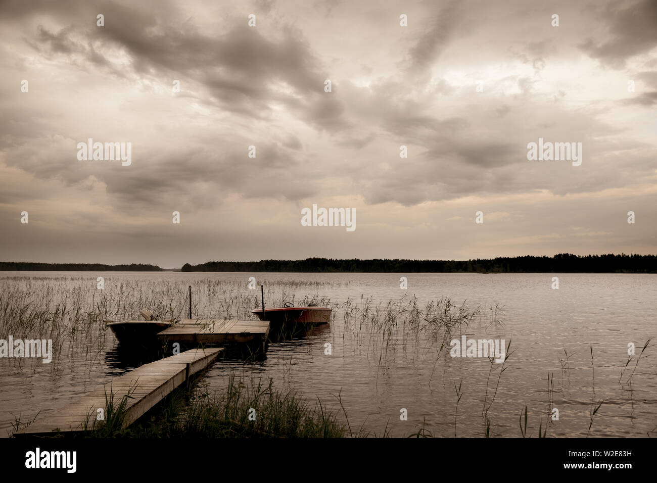 See mit dramatischen Himmel Boote und Holzsteg, natürliche Landschaft Stockfoto