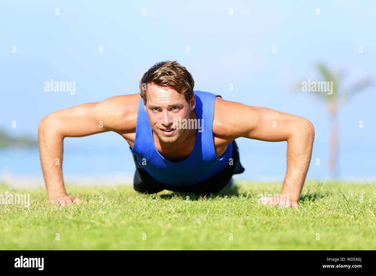 Push-ups - fitness Mann Training nach oben drücken, um draußen im Gras im Sommer. Passen männlichen Athleten, Cross Training Training im Freien. Kaukasische muskulös Sport Modell in seiner 20. Stockfoto