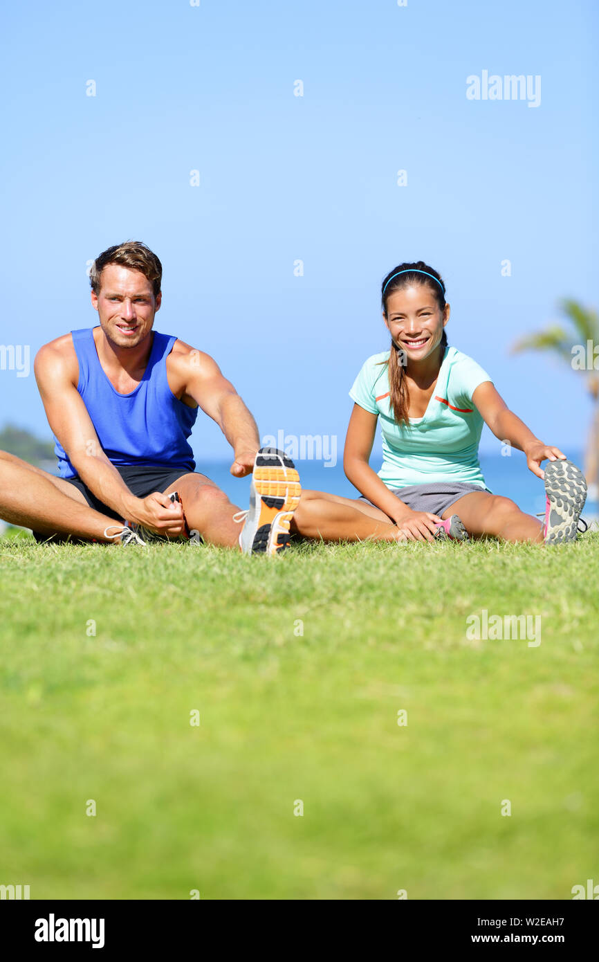 Fitness - paar Dehnübungen im Freien. Passen Mann und Frau tun Kniesehne bein Übung dehnen und strecken Training im Freien im Sommer. Schöne gemischtrassiges Paar. Stockfoto
