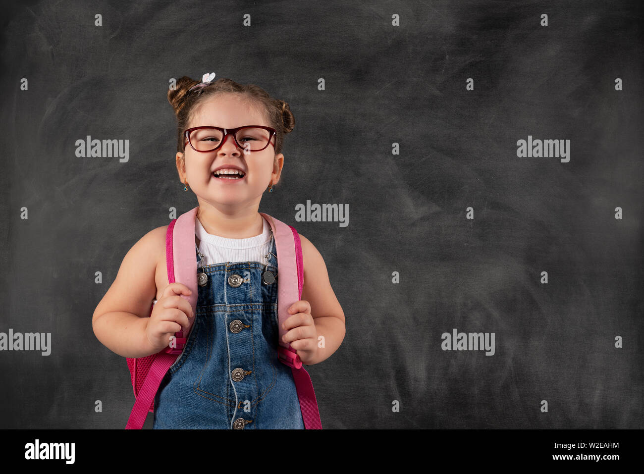 Kleinen niedlichen Kind mit Schultasche auf blackboard. Bildung Konzept Stockfoto