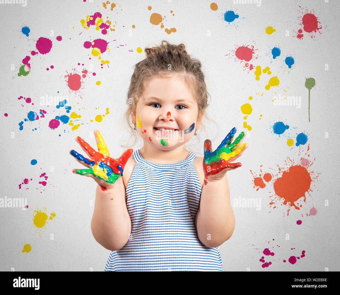 Lächelnde Mädchen mit Händen in der Farbe auf bemalten Wand Hintergrund Stockfoto