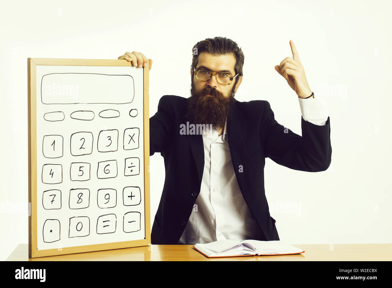Die Jungen gut aussehenden bärtigen Mann Wissenschaftler oder Professor in Lehrer Gläser mit langen Bart Holding mit Taschenrechner und Buch oder Briefpapier bei ta Sitzung Stockfoto