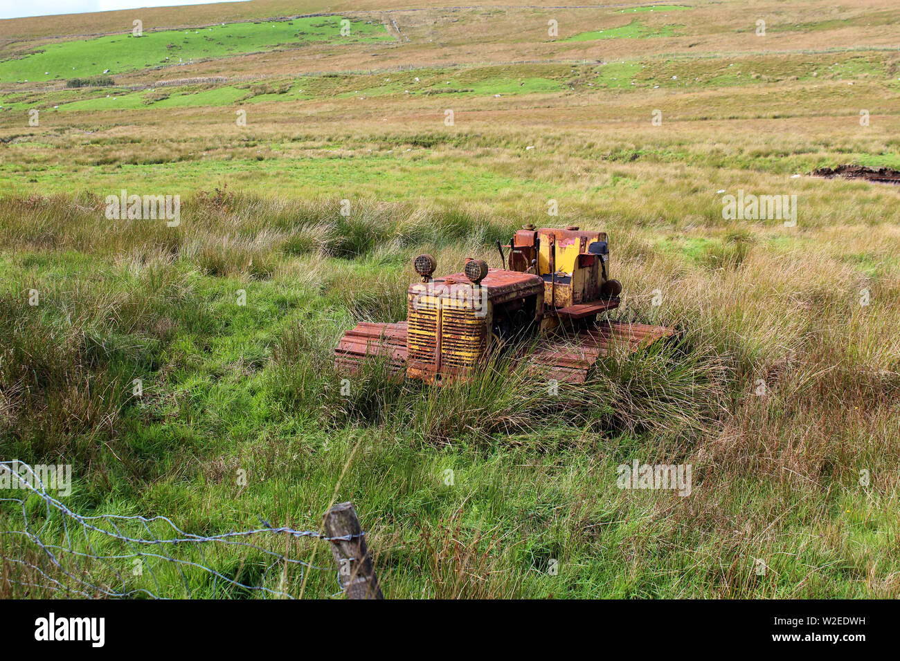 Rostig und zog sich auf der schottischen Grenze. Ein caterpillar Radtraktoren - rostigen alten landwirtschaftlichen Maschinen in der Galloway Hills, Schottland verlassen Stockfoto