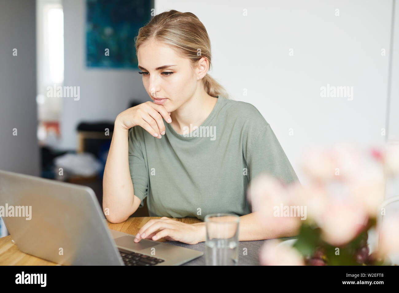 Junge weibliche Freiberufler in casualwear auf Laptop Display während Netzwerk zu Hause Stockfoto