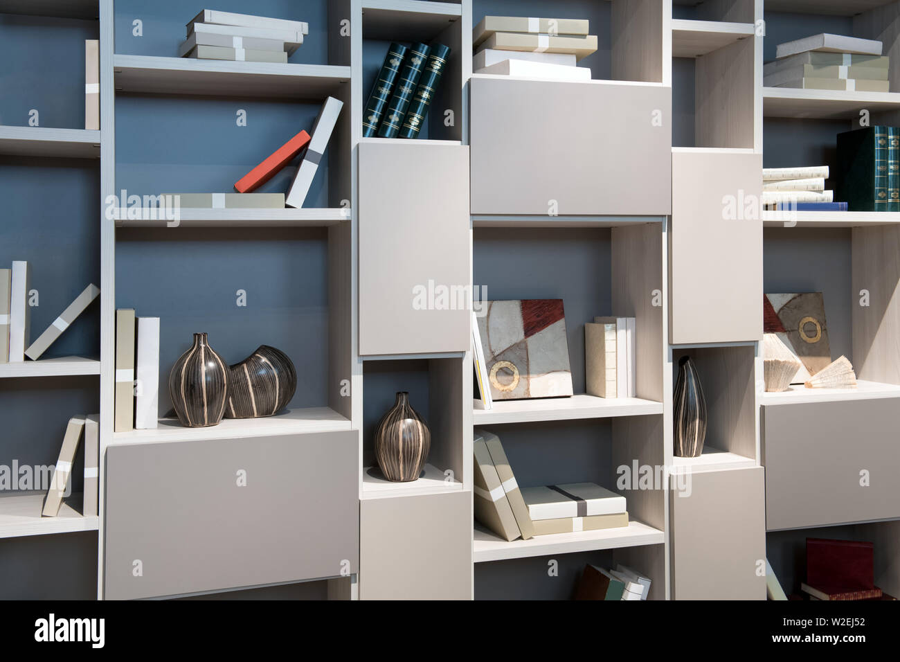 Moderne Bibliothek Schrank mit offenen Fachböden und Abschnitte in Neutral aus Weißen, die entlang der Wand eines Raumes für Bücher und Anzeige der Ornamente Stockfoto