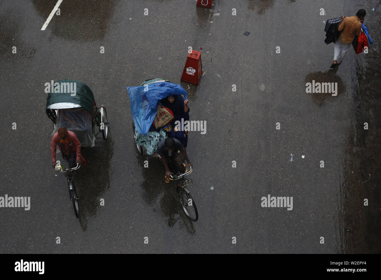 Juli 9, 2019 - Dhaka, Bangladesch - rikscha Passagiere nutzen Polyethylenfolie von Regen bei Regenwetter in Dhaka zu speichern. Eine tropische Depression anhaltende schwere Regenfälle in das Land zu bringen. (Bild: © MD Mehedi Hasan/ZUMA Draht) Stockfoto