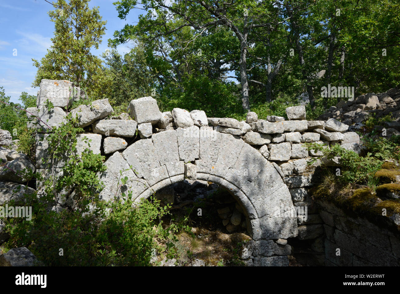 Teilweise begraben Steinbogen in zerstörten Gemeinschaftshaus oder Mittelalterliches Haus in Buoux fort, oder Fort de Buoux, Luberon Provence Frankreich Stockfoto