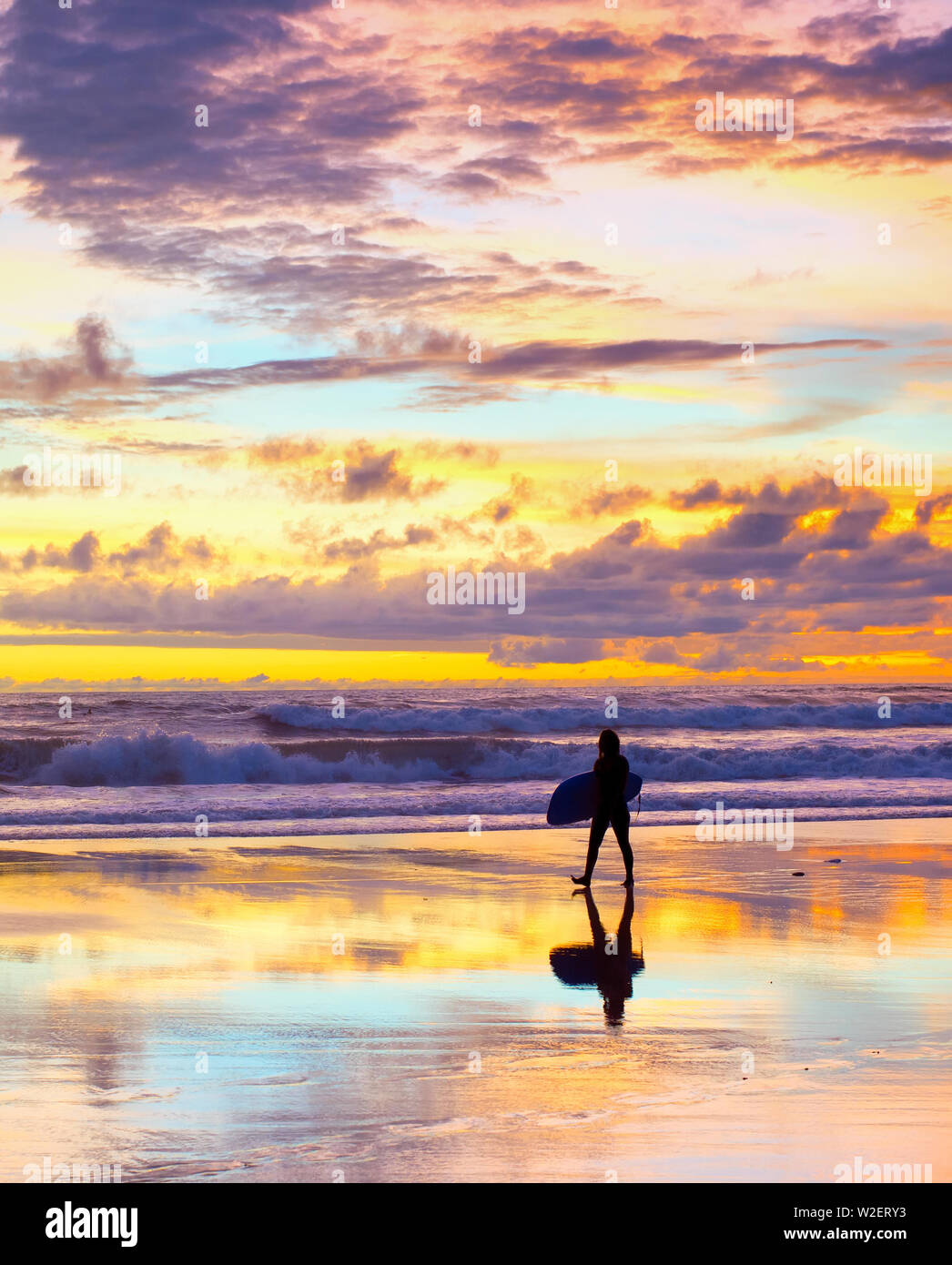 Silhouette der Surfer zu Fuß am Strand mit Surfbrett bei Sonnenuntergang. Bali, Indonesien Stockfoto