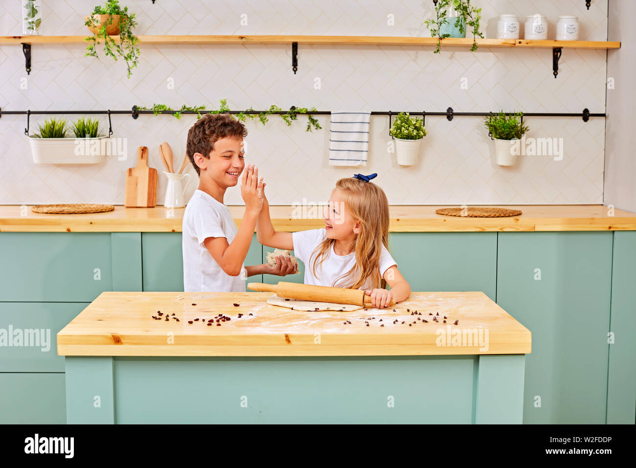 Glücklich liebende Familie bereitet Bäckerei zusammen. Bruder und Schwester sind Kochen, Cookies und Spaß in der Küche. Hausgemachte Speisen und wenig Hilfe Stockfoto