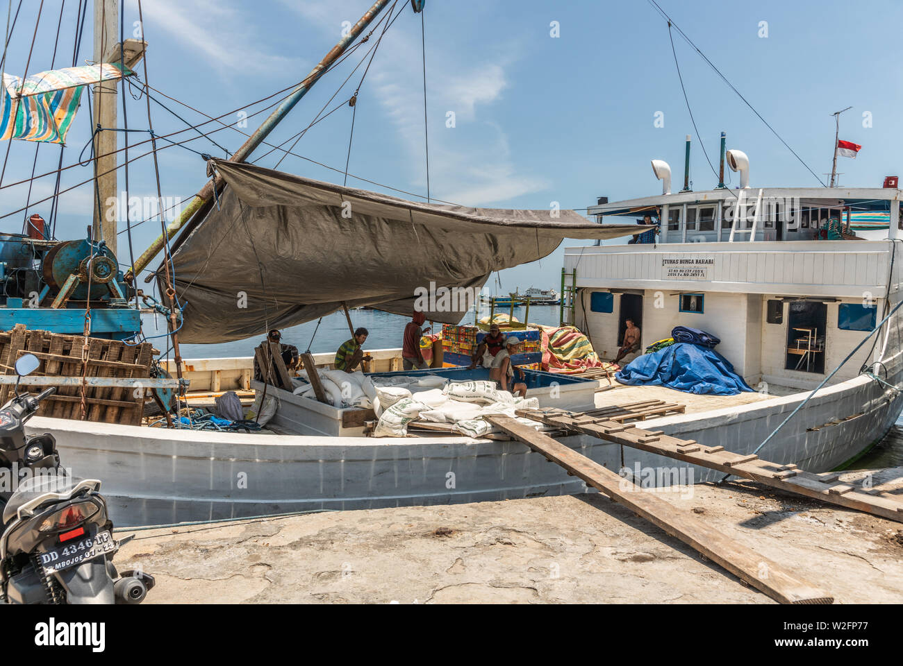 Makassar, Sulawesi, Indonesien - 28. Februar 2019: Paotere Alten Hafen. Männer nehmen eine Pause von manuell laden traditionelle Segelboot mit weißen Taschen u Stockfoto