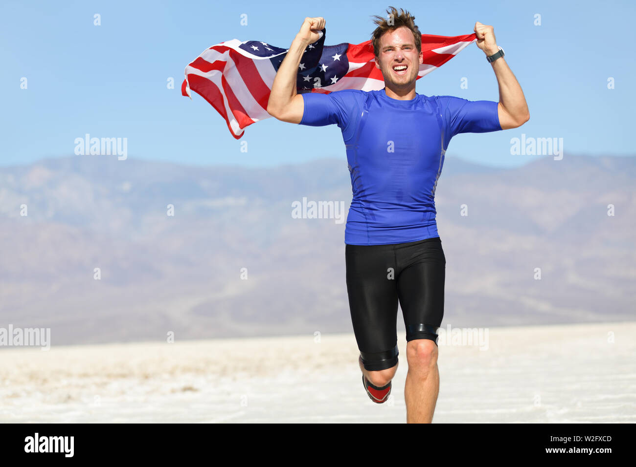 Runner Athlet Mann mit der amerikanischen Flagge - USA. Laufen Sport Fitness Mann mit US-Flagge. Athletischen jungen Mann zujubeln und läuft mit der amerikanischen Flagge in die Luft erhoben. Stockfoto