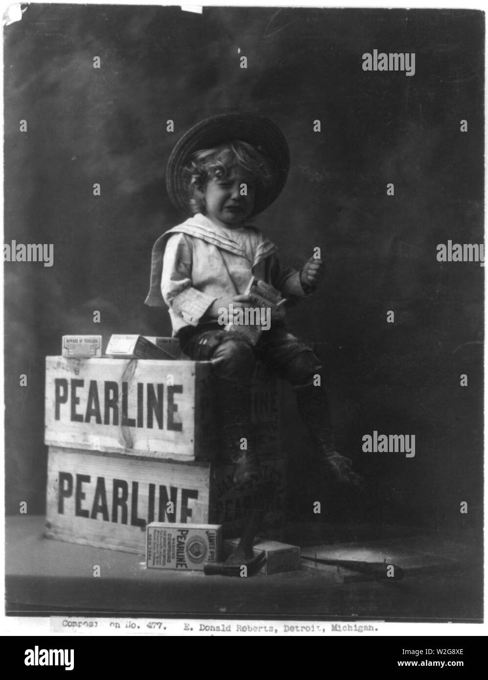 Kind auf der Kiste sitzt, Holding Box von pearline Compound waschen, und Weinen Stockfoto
