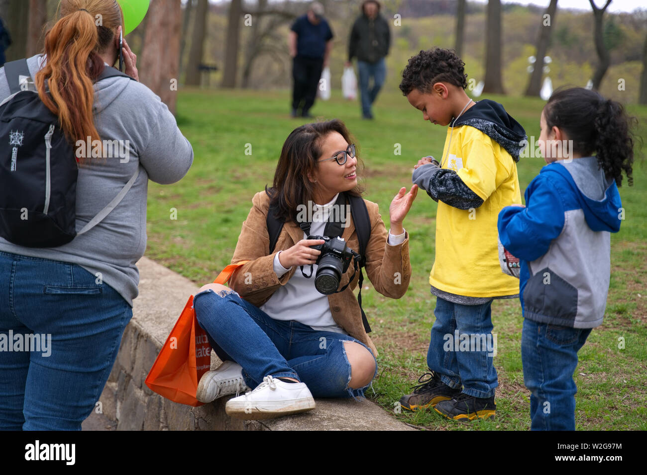 Meriden, CT USA. Apr 2019. Narzissenfest. Junge asiatisch-amerikanische Fotografin Interaktion mit einem Multi Rasse Familie. Stockfoto