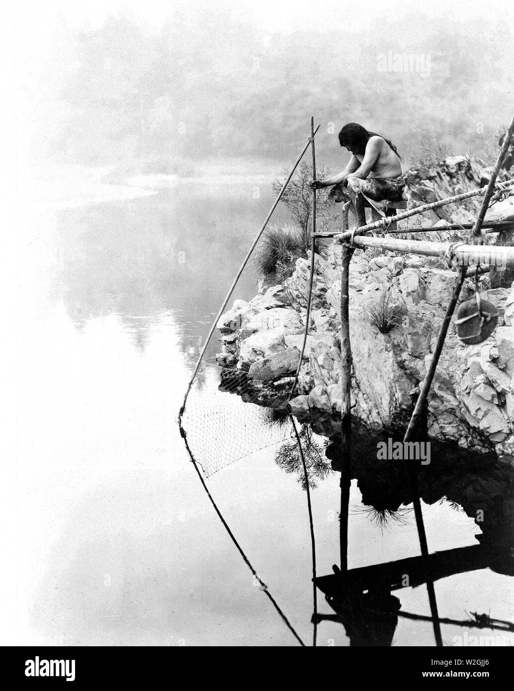 Edward S. Curits Native American Indians - hupa Indischen auf der Plattform über dem Wasser mit einem Fischernetz Ca. 1923 Stockfoto